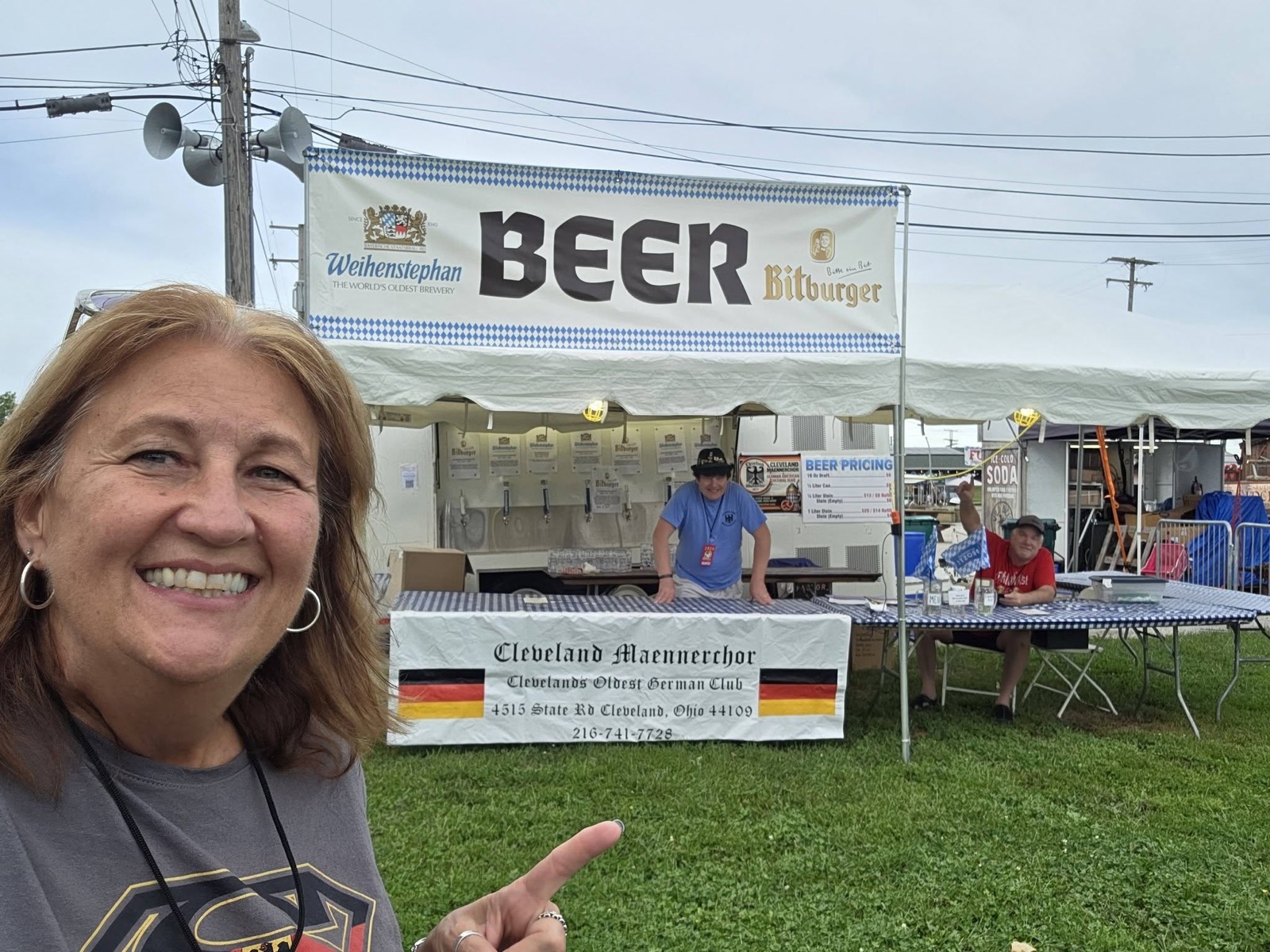 Smiling volunteer in front of the Cleveland Maennerchor beer trailer under a BEER banner at the Cleveland Oktoberfest